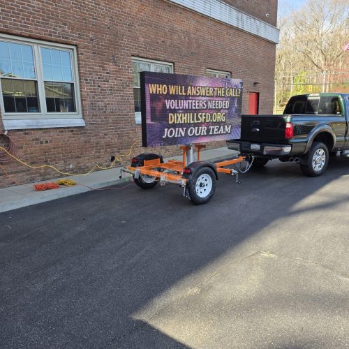 Truck towing volunteer recruitment sign in parking lot.