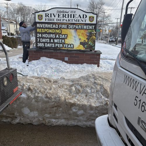 Person adjusting Riverhead Fire Department sign.