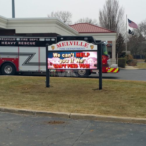 Fire department truck and sign outside building.