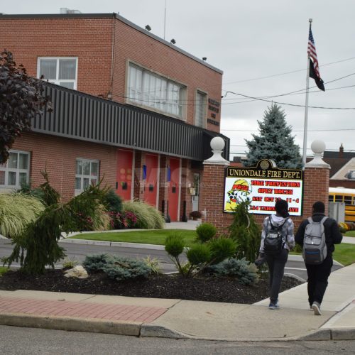 People walking past a red brick building.