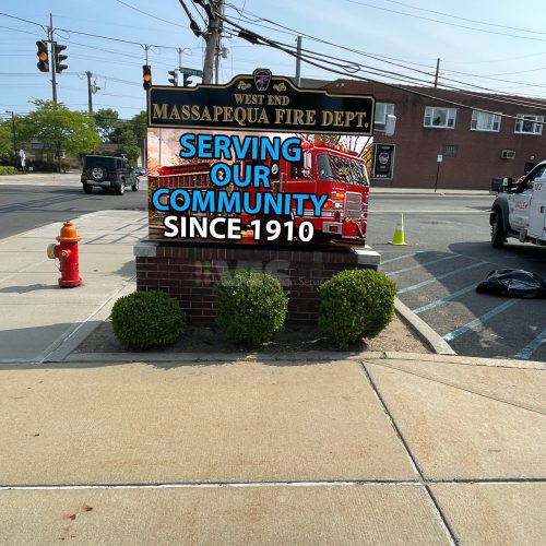 Massapequa Fire Department sign on sidewalk.